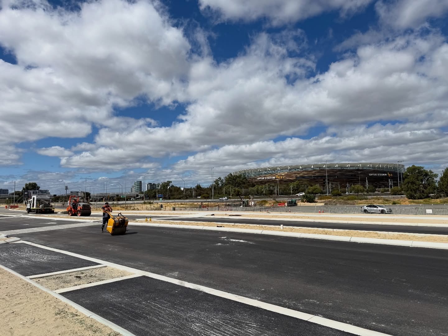 YongaCivil freshly laid asphalt car park and roads with line marking near Perth's Optus Stadium, with a roller compacting the surface