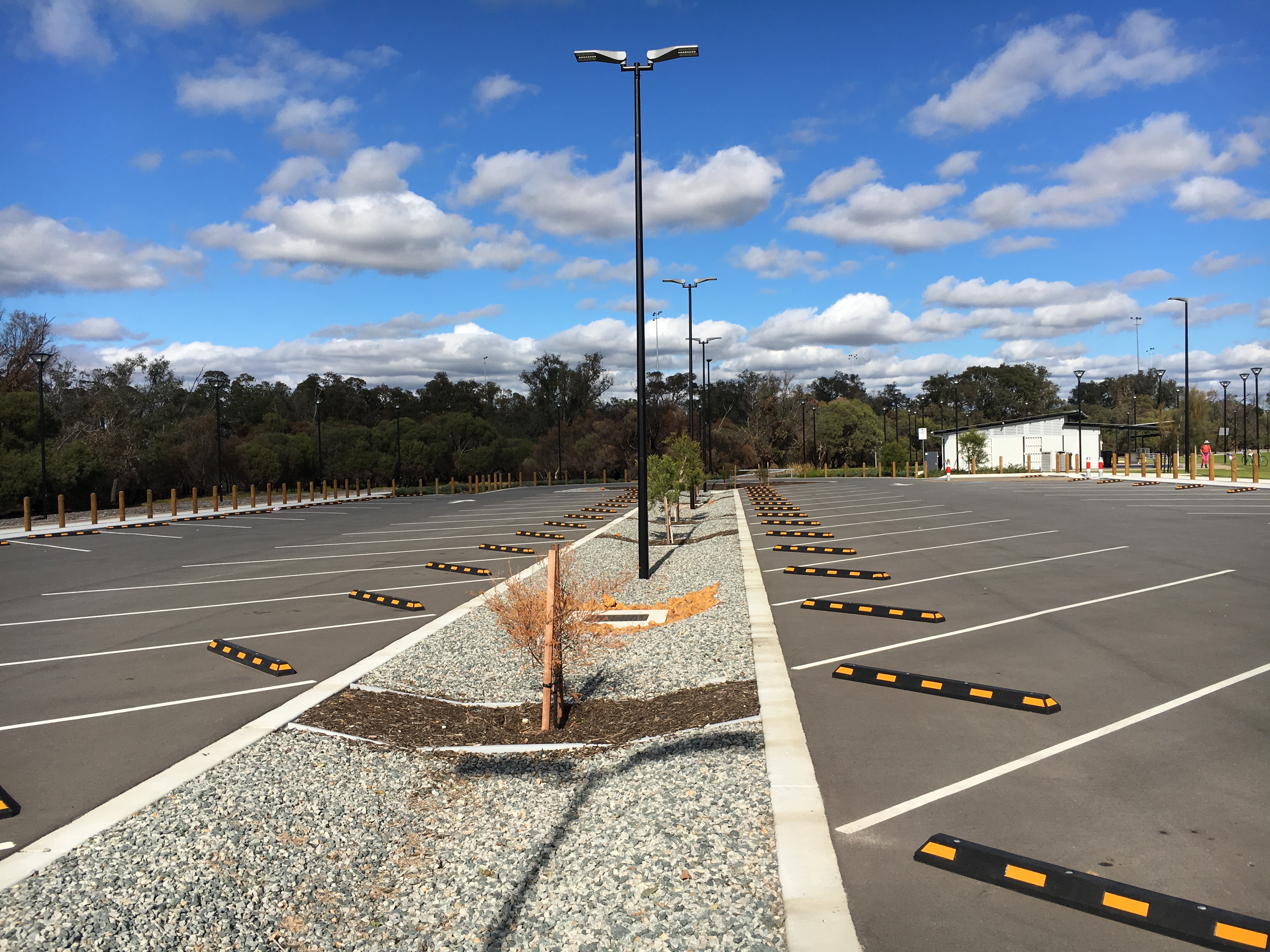 Completed commercial parking facility with line-marked bays, wheel stops and concrete-kerbed landscaped medians built by YongaCivil in Western Australia