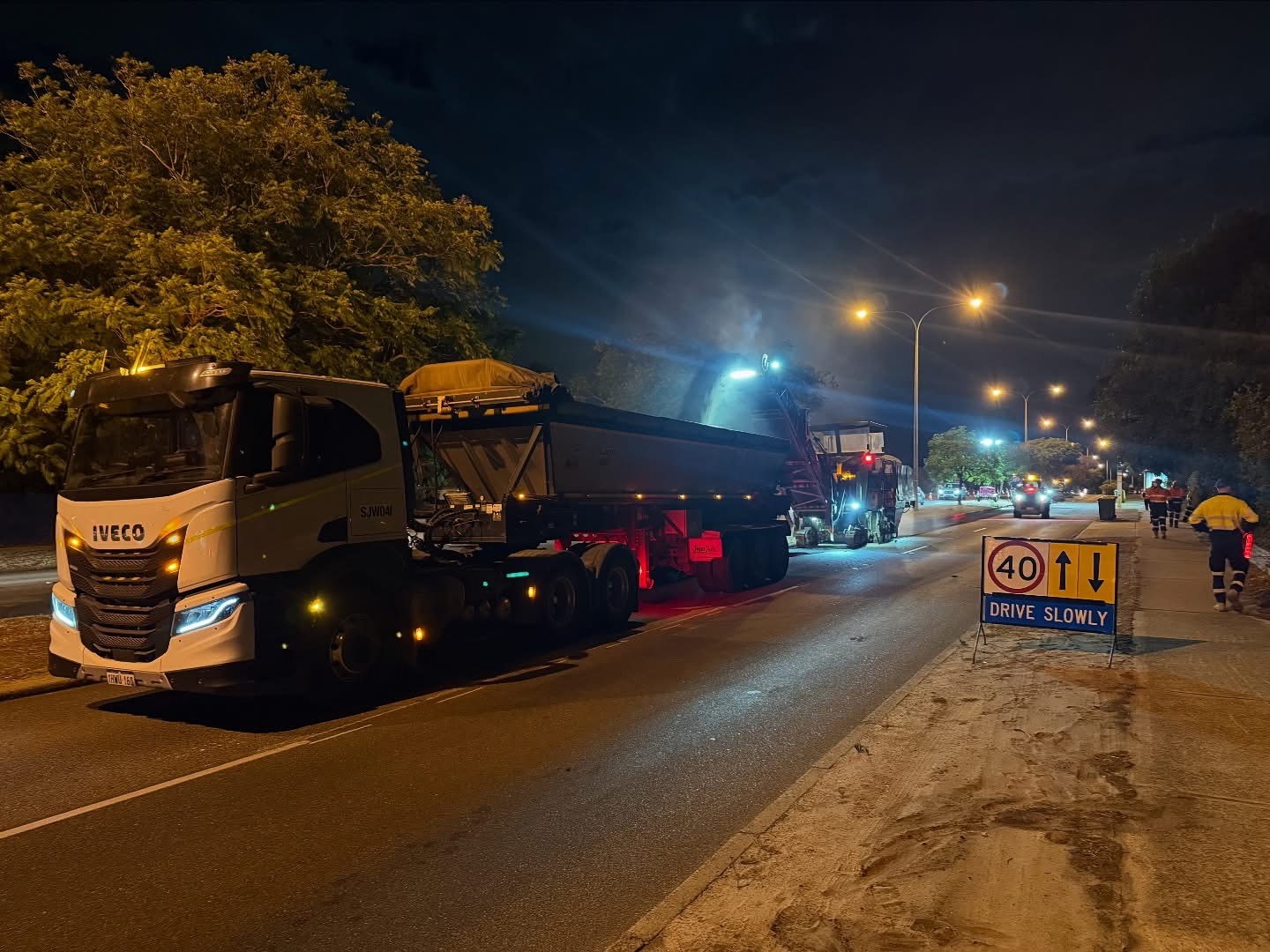 YongaCivil night-time road profiling operation on a Western Australian road with an IVECO tipper truck, cold-milling machine, traffic management signage and hi-vis crew