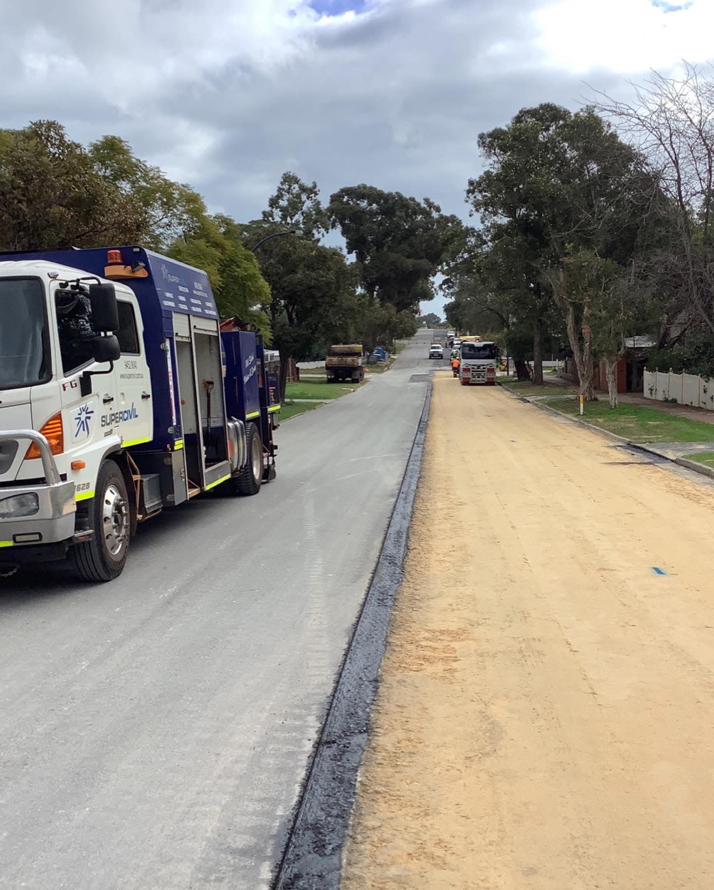 YongaCivil service truck on a suburban Western Australian street during road reconstruction, with one lane freshly sealed in new asphalt and the other stripped back to sand base